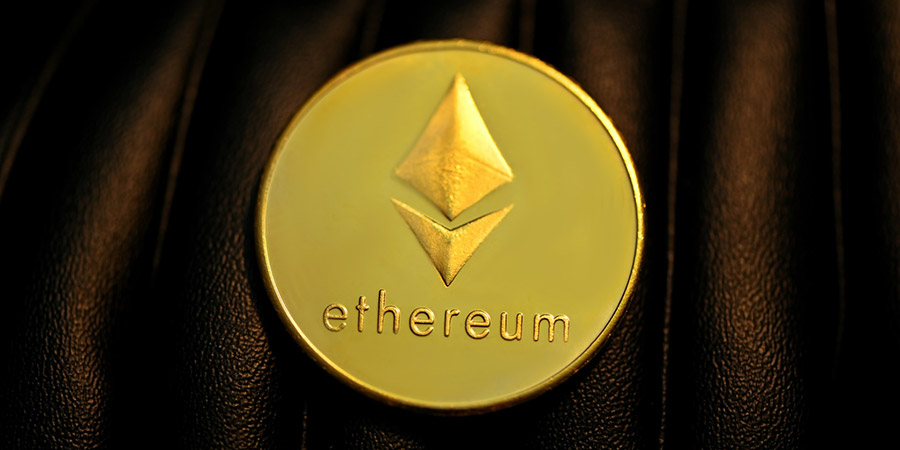 Ethereum gold coin on top of a black leather surface